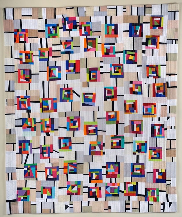 Colorful quilt with geometric patterns and abstract designs in various colors, including red, blue, green, yellow, and pink, with a predominantly white background and black and beige accents.