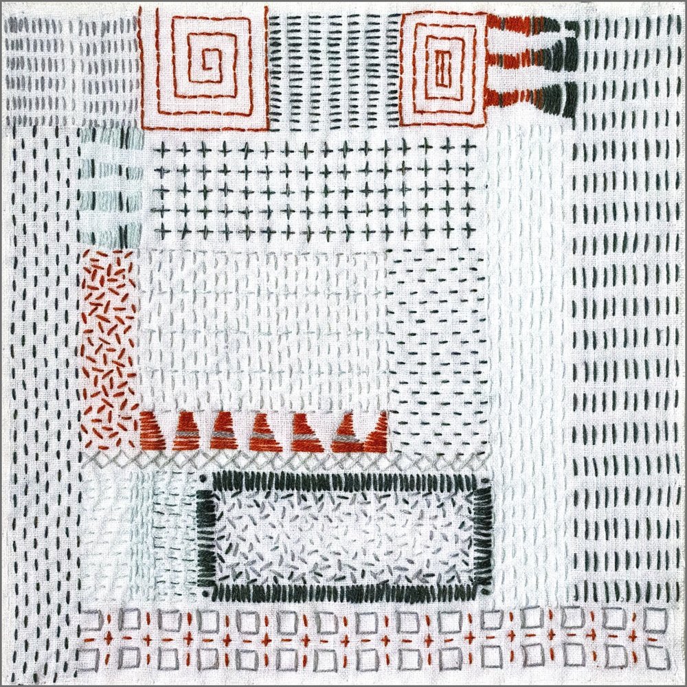 A piece of embroidered fabric with various geometric and abstract patterns in red, green, black, and white thread.