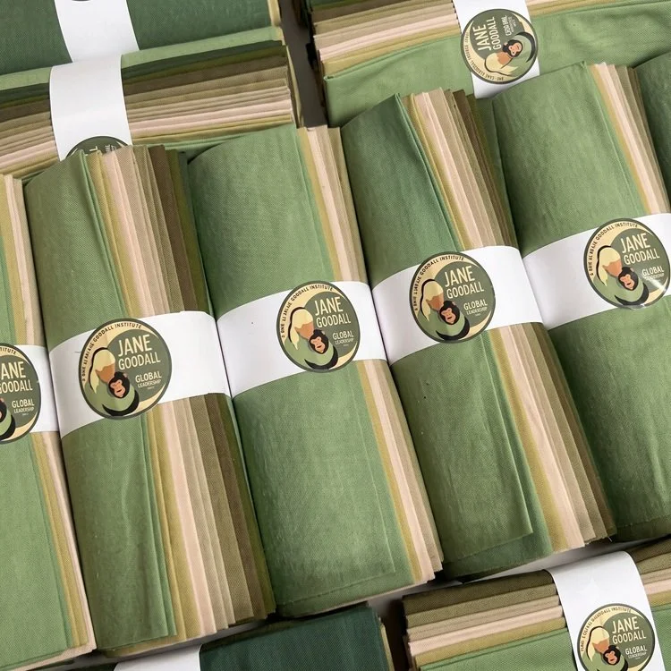 Multiple rolled sets of fabric with a Jane Goodall Institute label, predominantly green in color.