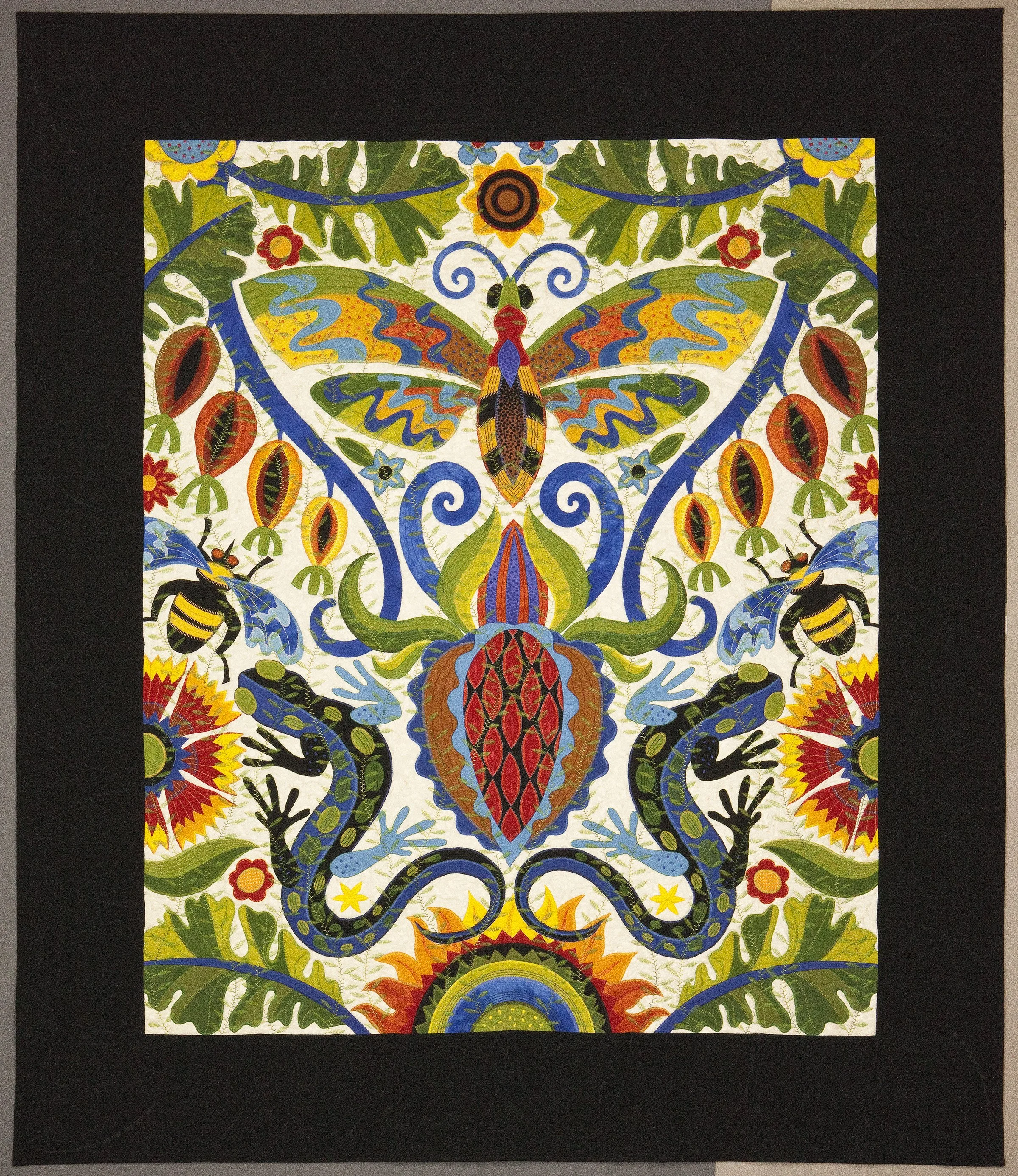 A brightly colored textile with a symmetrical design featuring a prominent butterfly at the center, surrounded by floral and leaf motifs, set on a black background.