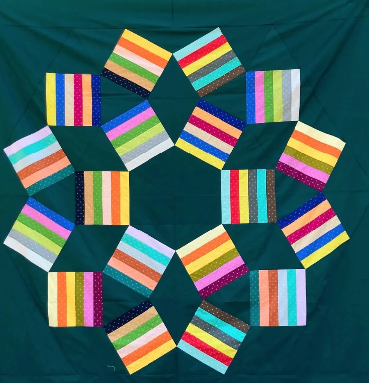 Colorful, striped fabric squares arranged in a star-like pattern on a dark green background.