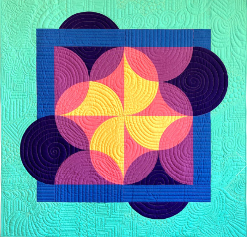 Colorful geometric quilt with circles, squares, and spiral patterns in shades of pink, yellow, purple, blue, and green.