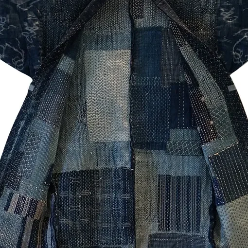 Close-up of a blazer made from different patches of Japanese denim fabric in various shades of blue.