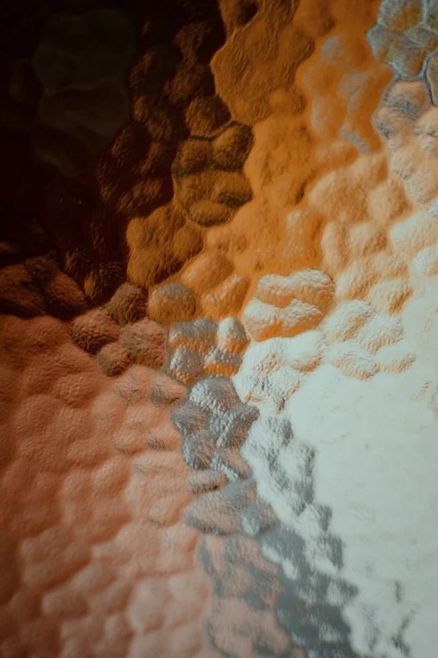 Close-up of a textured surface with multiple overlapping layers of honeycomb-like structures in shades of orange, brown, and white.