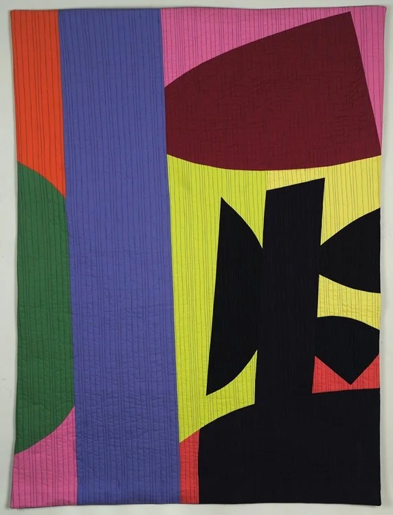 Abstract multicolored quilt with vertical stripes and a large black Chinese character in the center.