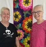 Two women smiling in front of a colorful floral background