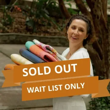 A woman holding a stack of folded towels outdoors with a "Sold Out" and "Wait List Only" banner overlay.
