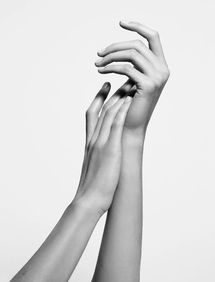 Two hands gently touching, with the fingers of one hand resting on the fingers of the other, in black and white.