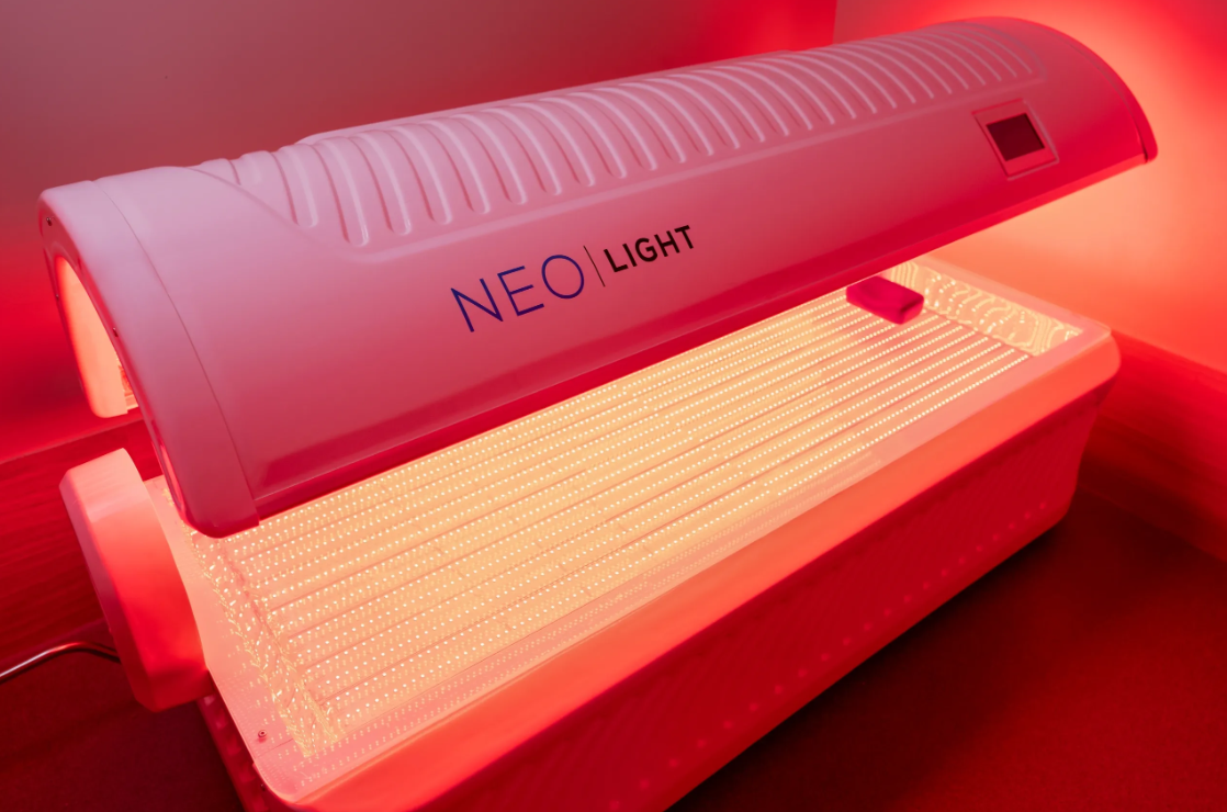 Red light therapy device labeled 'NEO LIGHT' emitting red light beams.