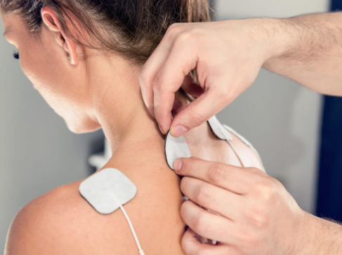 Person applying E_STIM medical patches to the shoulder and neck area.