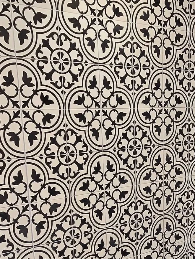 Patterned black and white tile wall with ornate floral and circular designs.