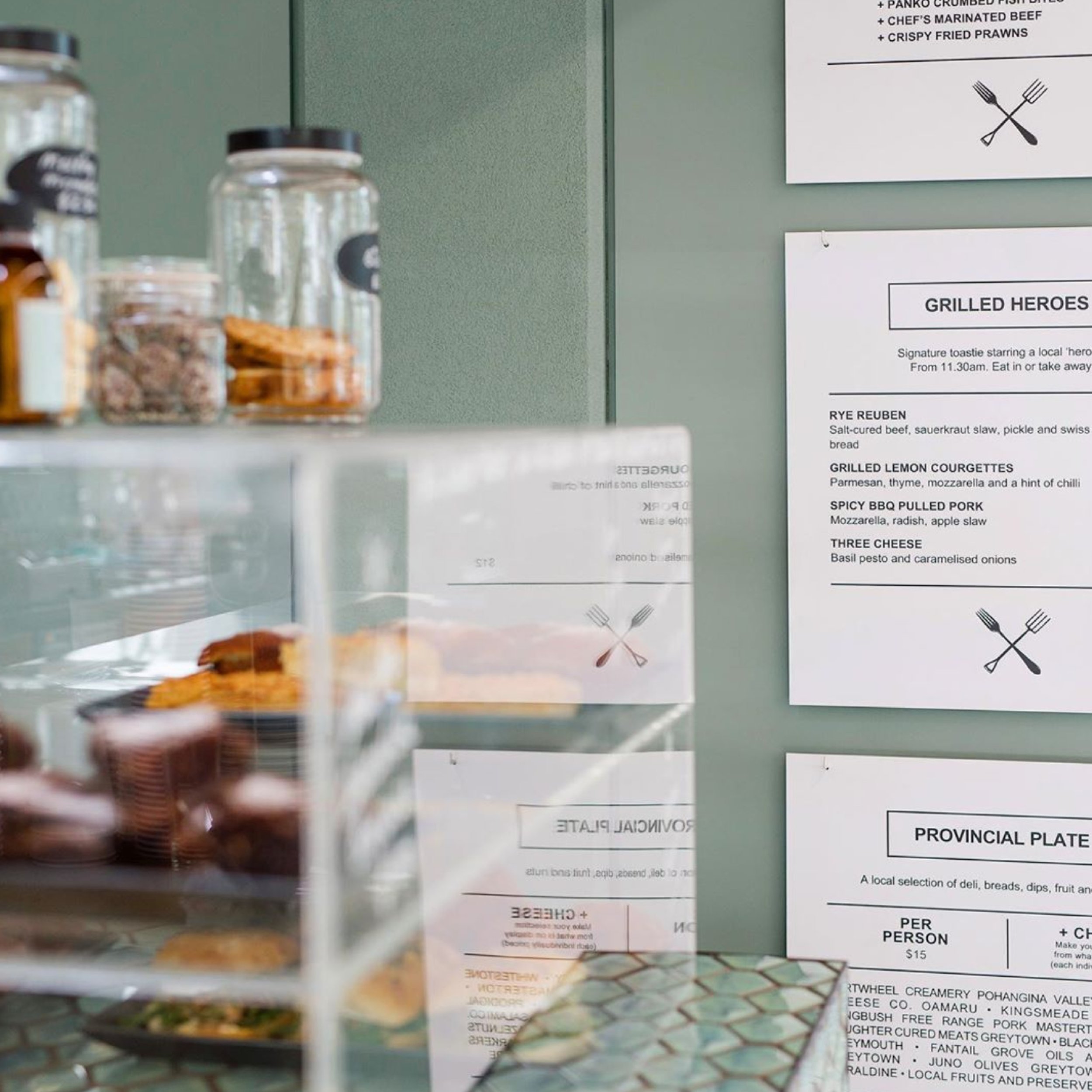 Local cafe and eatery menu next to cabinet of food. Branding, hospitality design, interior architecture, menu design, print, designer, Creative Director. Alice Lloyd.