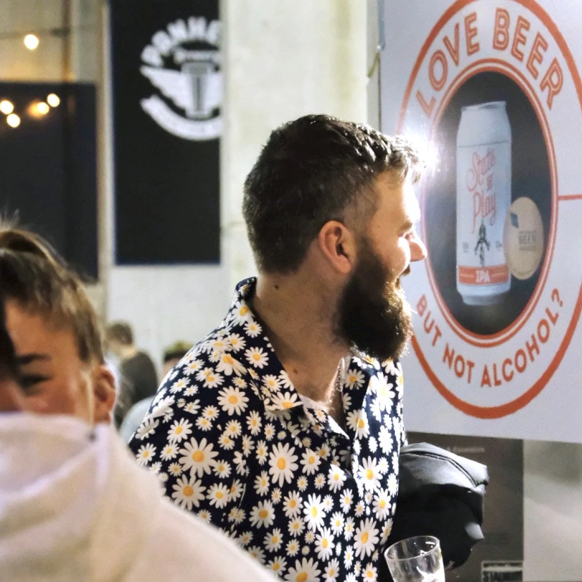 Man laughs as he checks out the State of Play Beervana stand. Sign behind says 'Love beer, but not alcohol?'. Photography, packaging design, branding, designer. Alice Lloyd.