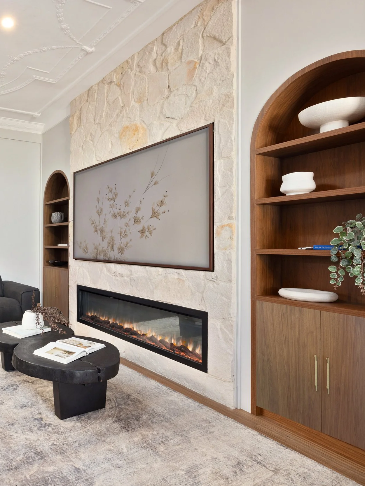 Living room with a modern fireplace, sandstone feature wall, wooden built-in shelves, walnut, electric fireplace