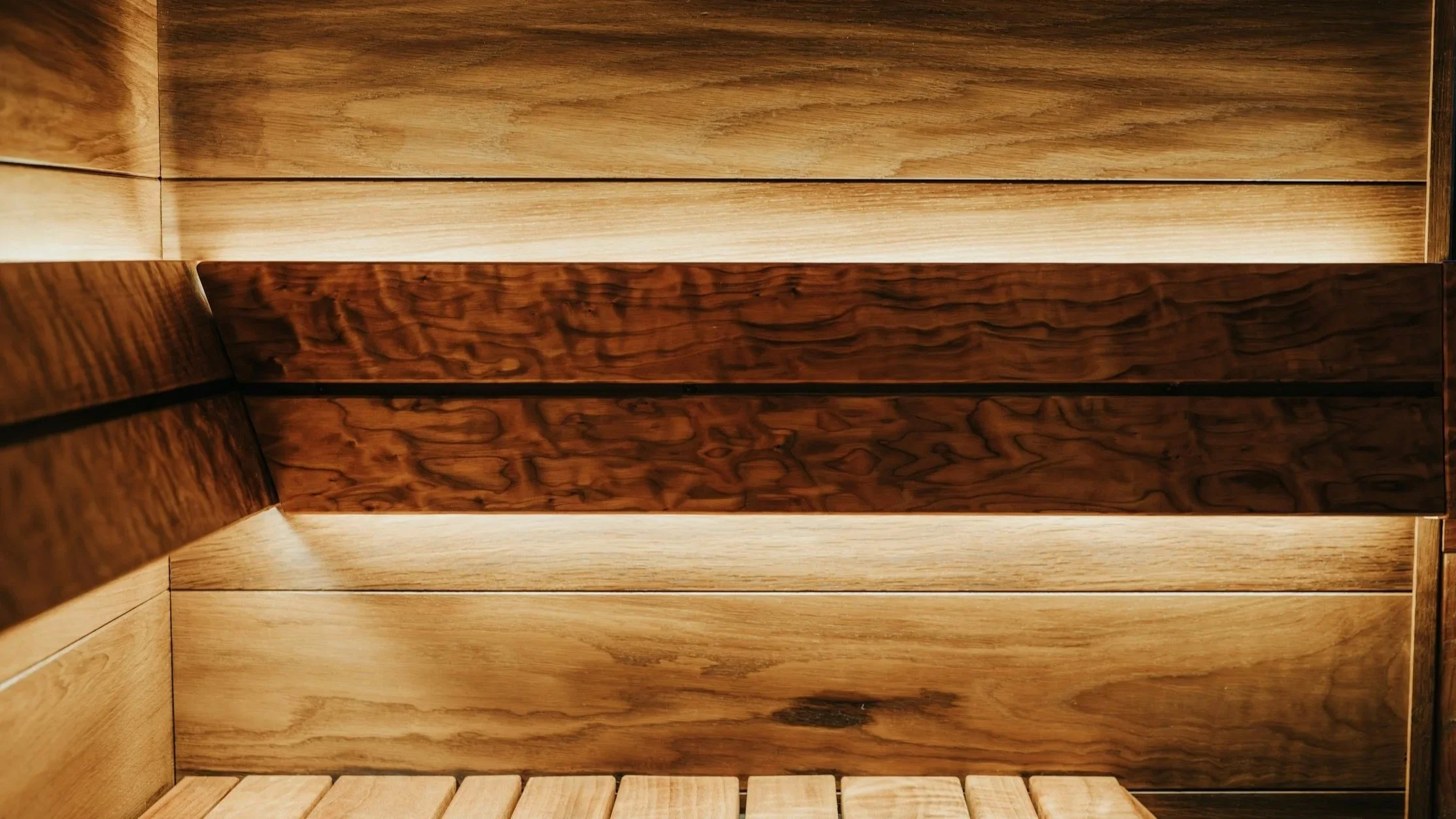 Close-up of wooden interior panels with two shades of wood, light and dark, with visible grain patterns.