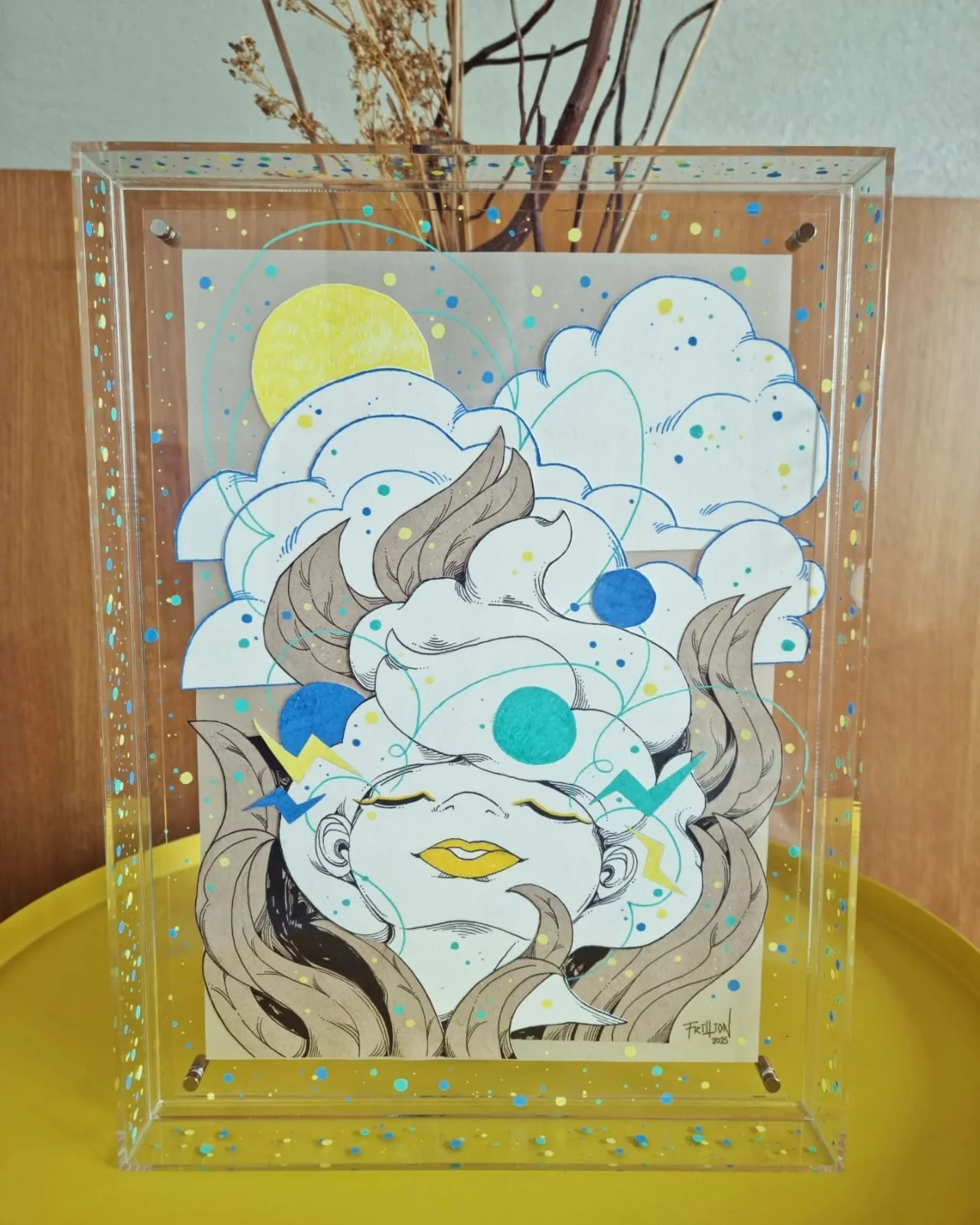 Artistic illustration of a woman's face with closed eyes and flowing hair, surrounded by clouds, a yellow sun, and abstract colorful dots and lines inside a clear box.