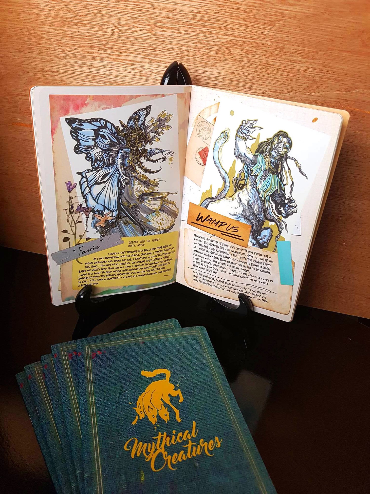 Open book showcasing illustrations of mythical creatures, including a butterfly-mermaid hybrid and a lion with a lion's head, on a wooden table with tarot cards below.