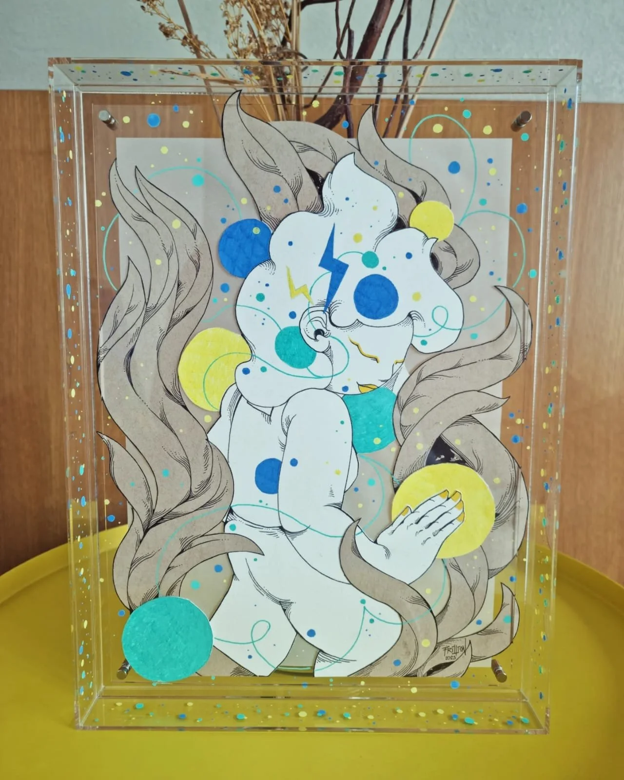 A drawing of a woman with long, flowing hair surrounded by blue and yellow circles, lightning bolts, and bubbles inside a transparent box with a yellow base and colorful confetti-like dots.