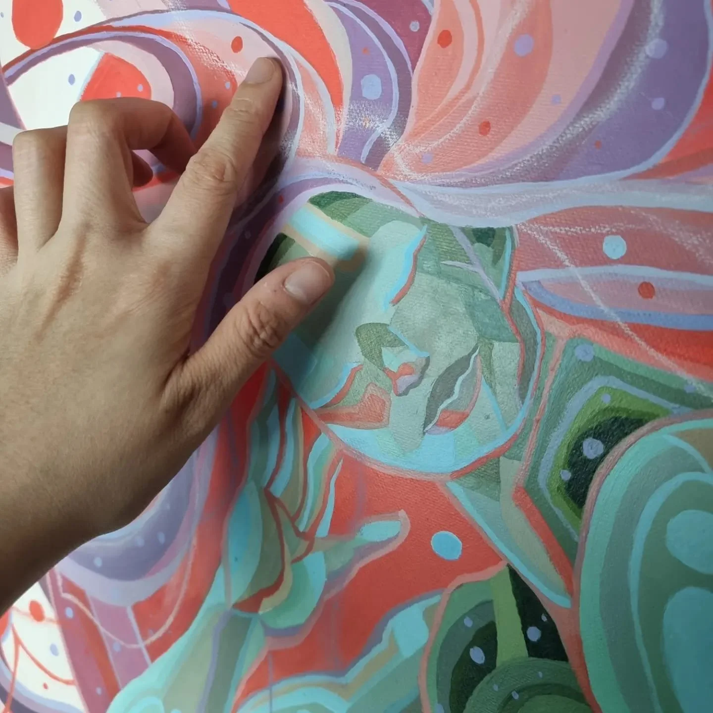 Close-up of a person's hand touching a colorful abstract painting with swirling patterns and various shades of pink, green, blue, and purple.