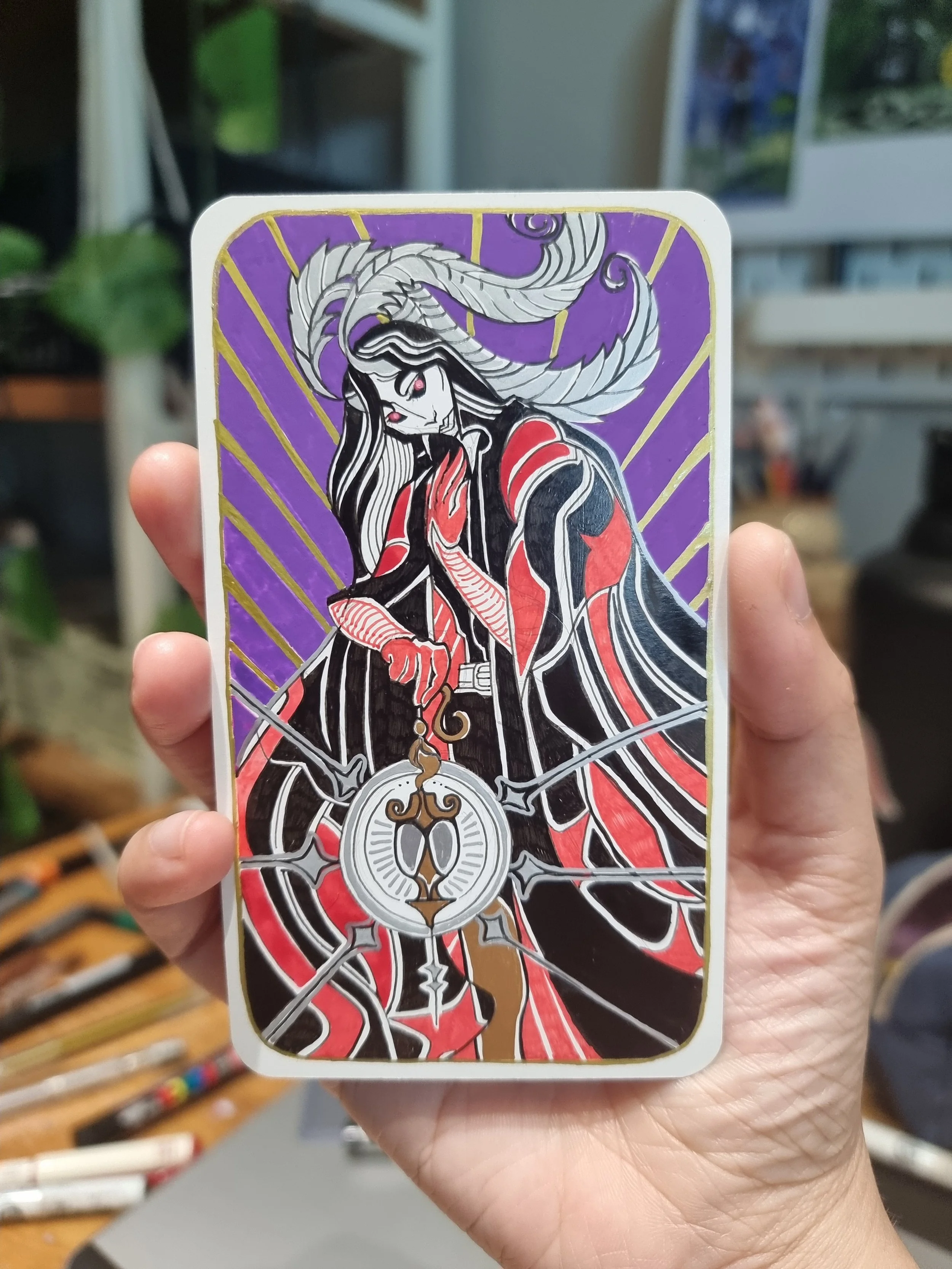 A tarot card featuring a woman with long, flowing hair, wearing a red and black outfit, and holding a sword. The background is purple with gold lines radiating outward.