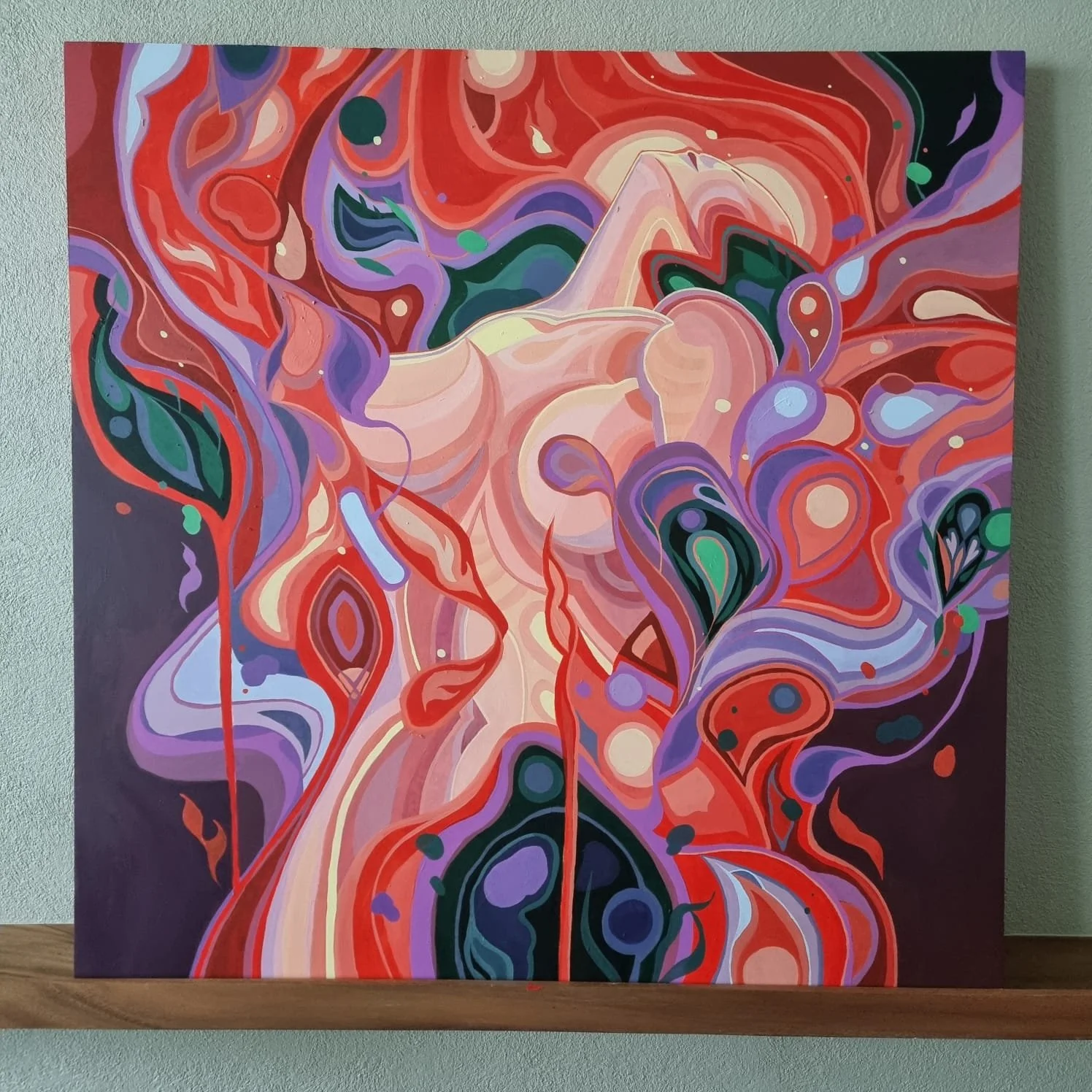 Abstract colorful painting with swirling shapes and lines in red, purple, green, black, and beige tones, mounted on a wall.