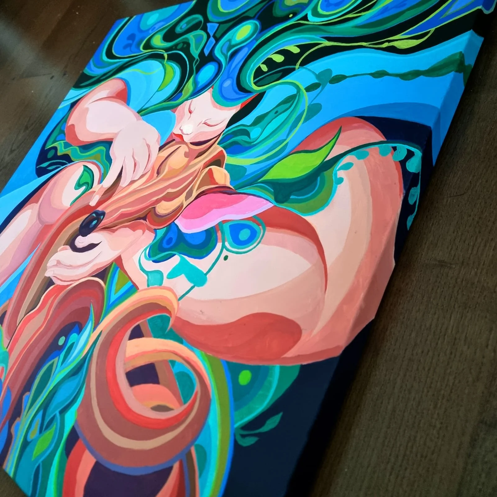 A colorful abstract painting on a canvas featuring a woman with long flowing hair, surrounded by swirling patterns in shades of blue, green, pink, and beige.
