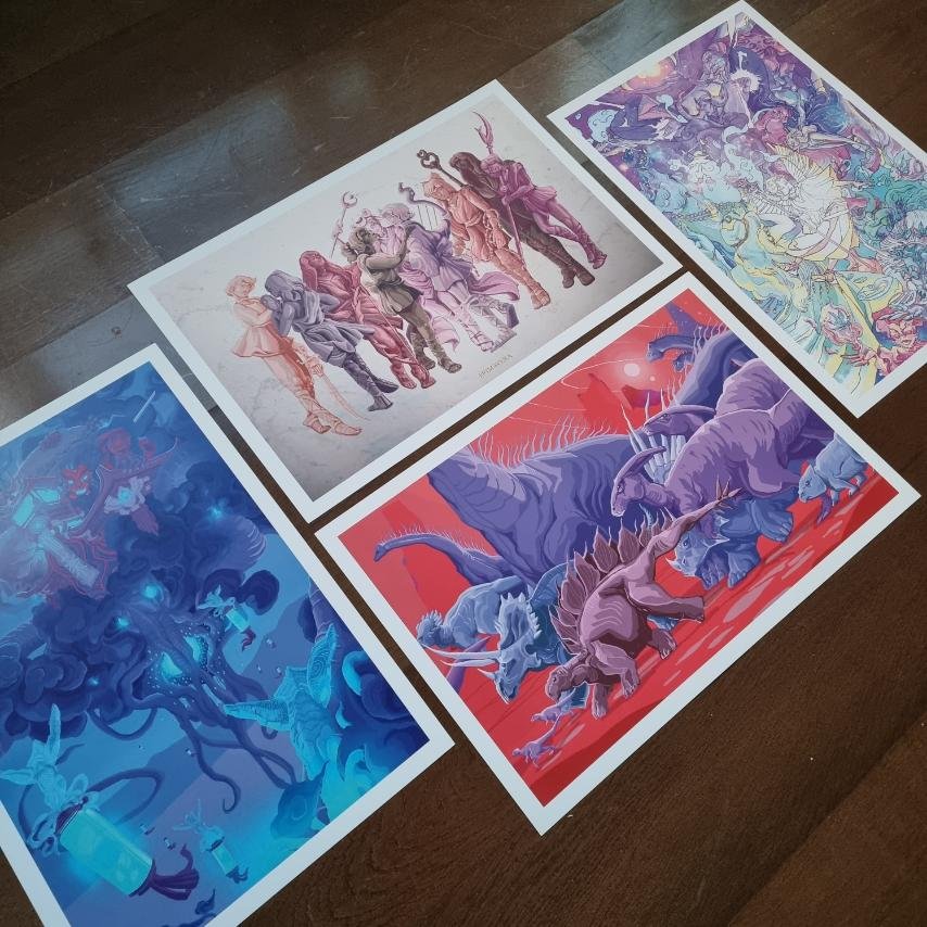 Four printed illustrations laid out on a dark wood surface, depicting fantasy scenes with mythical creatures and characters.