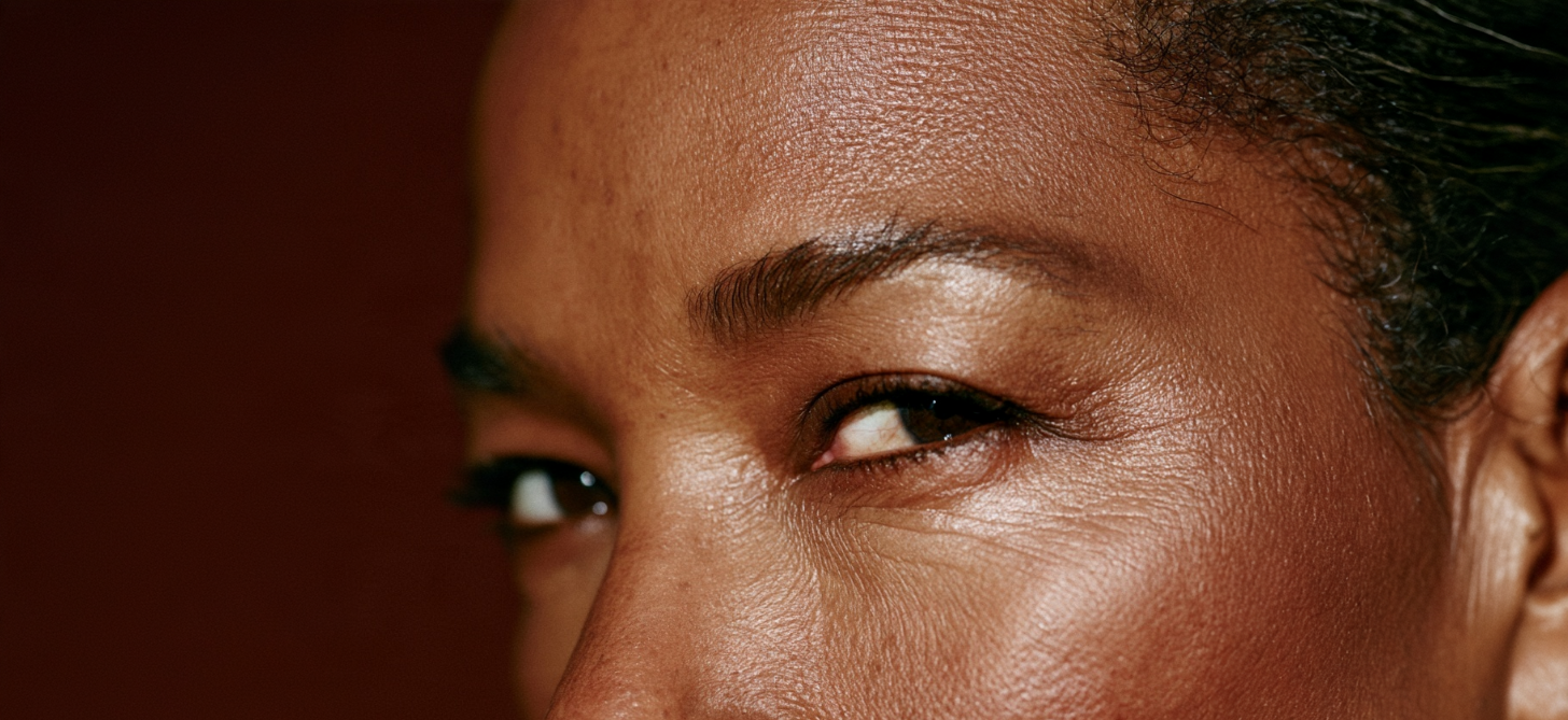 Close-up portrait of a mature Black woman highlighting her eyes, natural skin texture, and subtle expression lines