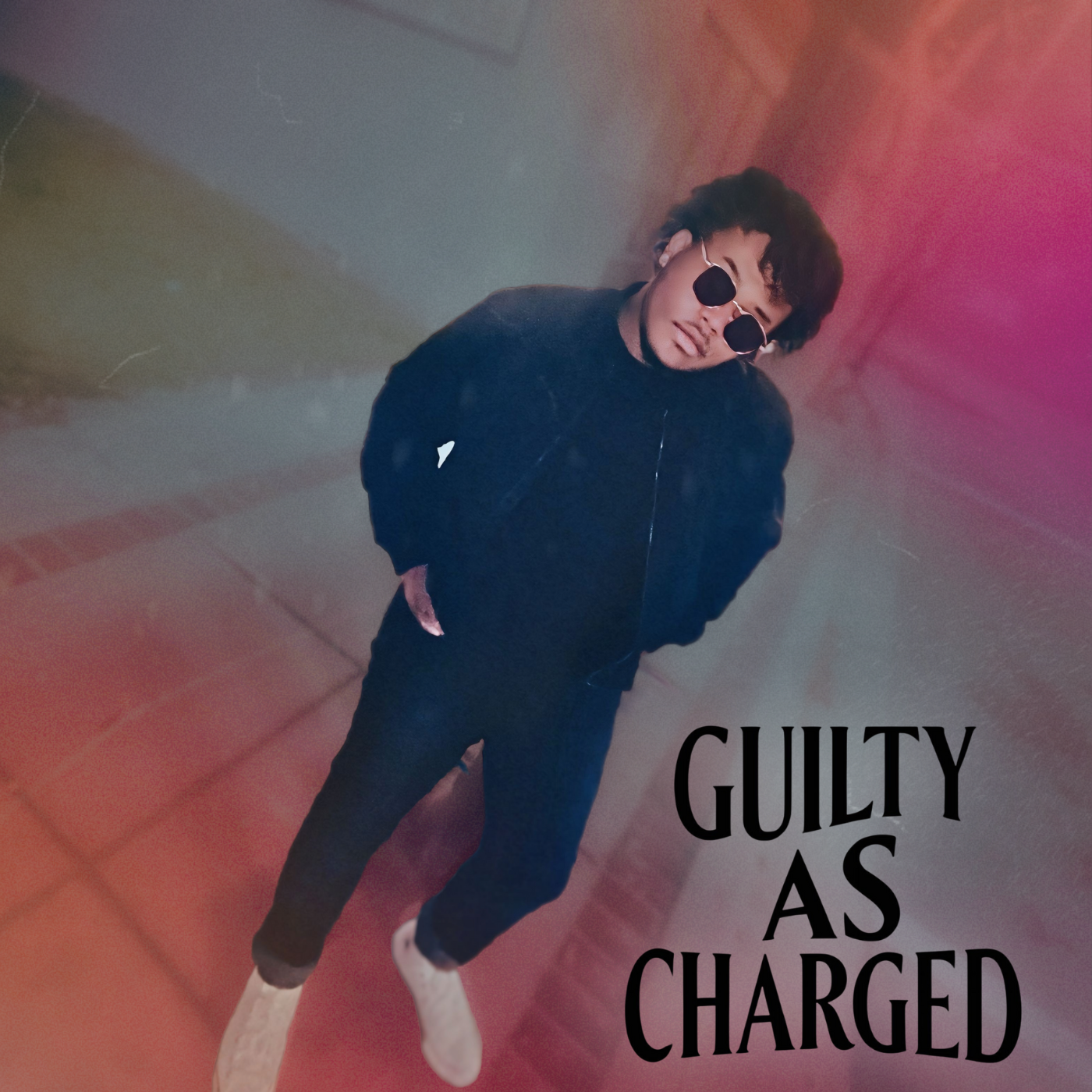 A young man with curly hair, wearing sunglasses, a black jacket, black pants, and white sneakers, standing with hands in pockets against a colorful, graffiti-like background. The text "GUILTY AS CHARGED" appears on the lower right of the image.