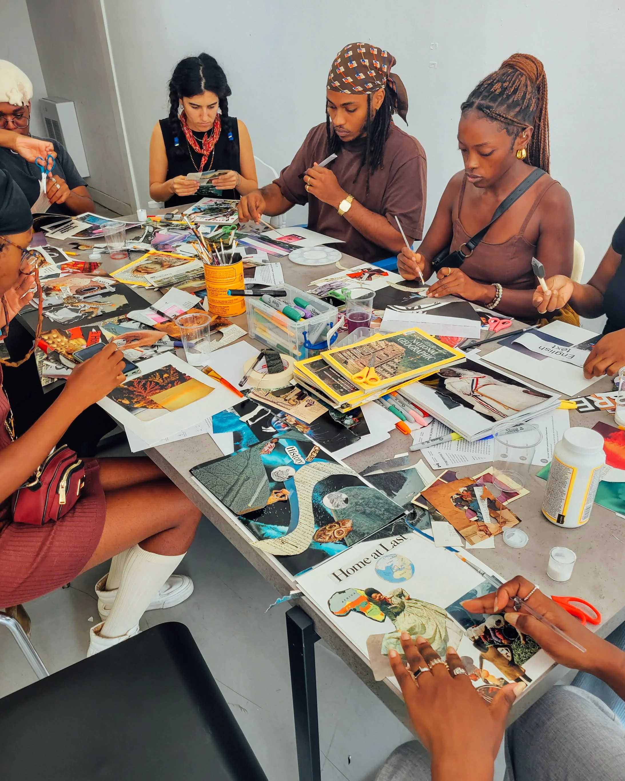 Groupe de personnes réalisant un projet créatif avec des images et des magazines sur une table.