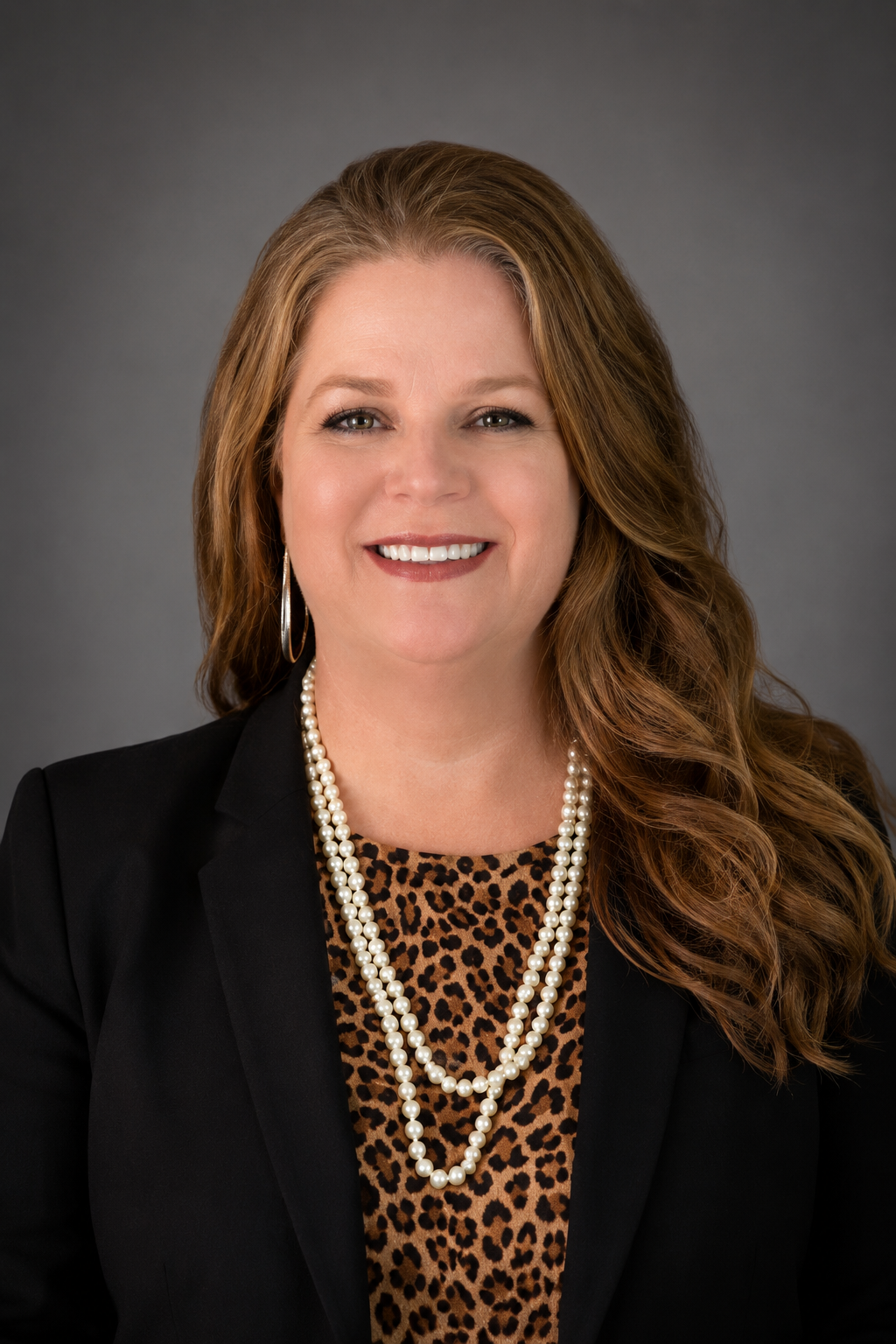 woman with leopard shirt and black jacket in front of grey background