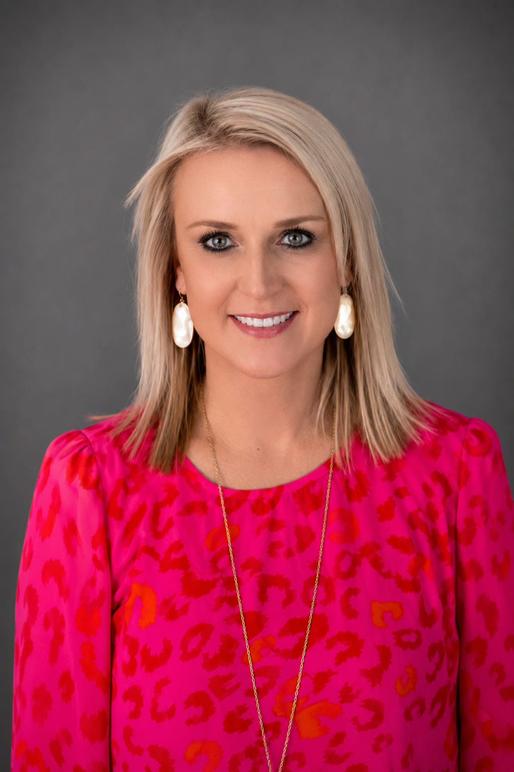 blonde woman with pink shirt in front of grey background