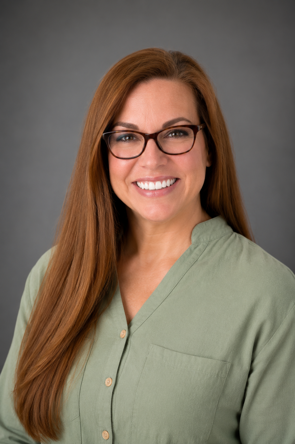 woman with glasses and green shirt in front of grey background