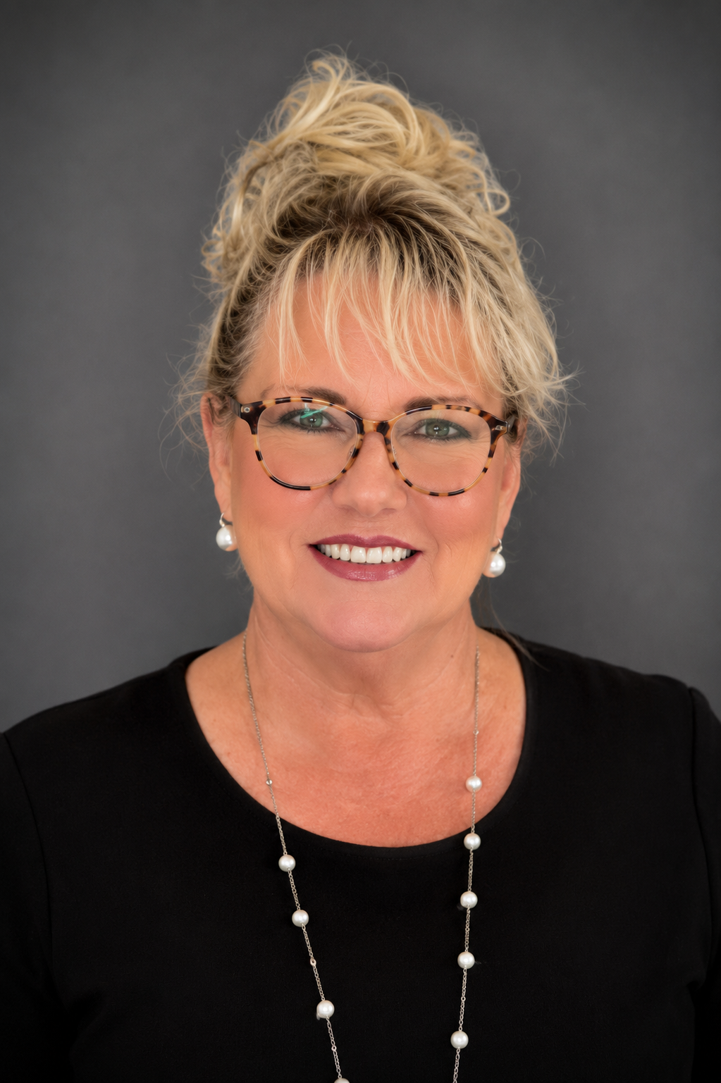 woman with black shirt and glasses in front of grey background
