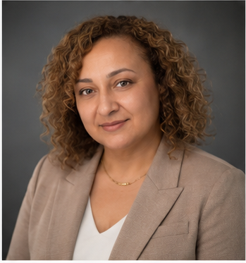 Woman with curly hair and tan jacket in front of grey background