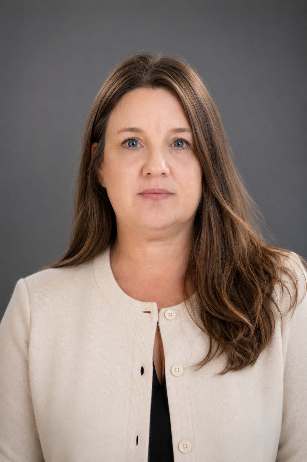 woman with brown hair and tan sweater in front of grey background