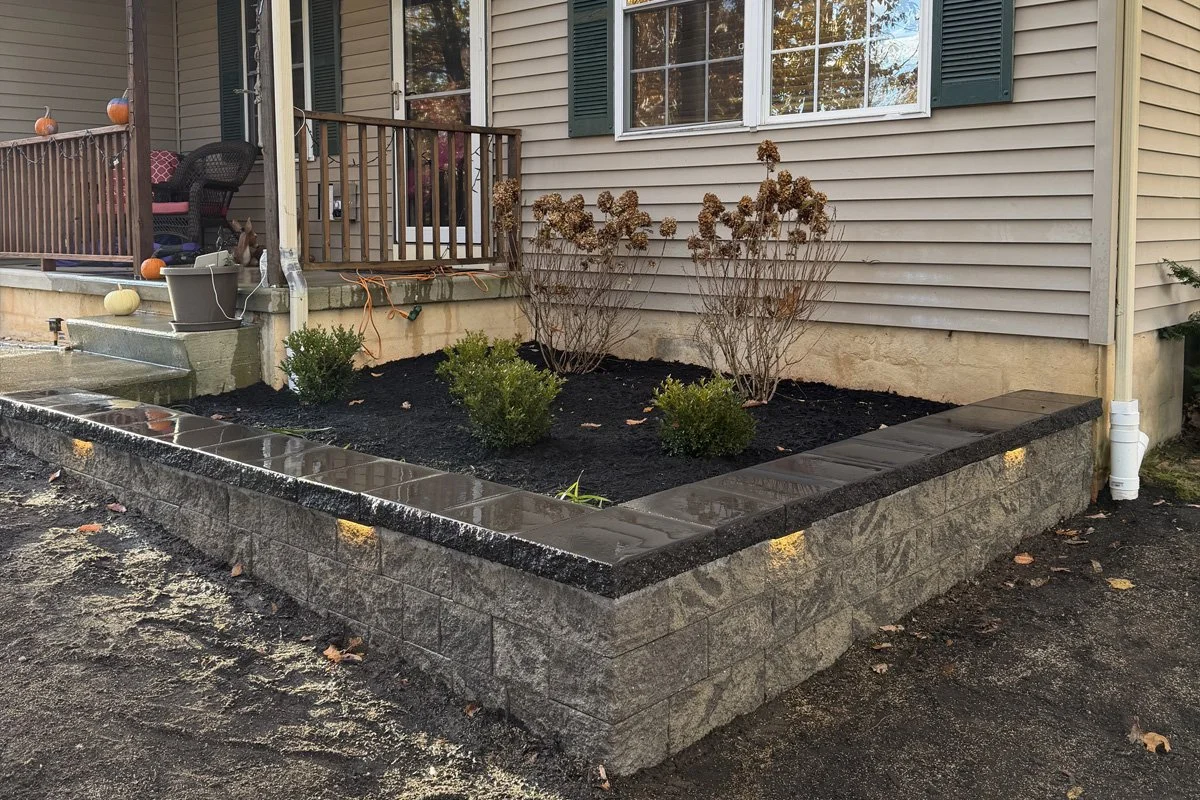 A garden wall installation of Cambridge Maytrx 6 wall block in natural/onxy color, coal cambridge caps, and low voltage undercap lights in Atco, NJ