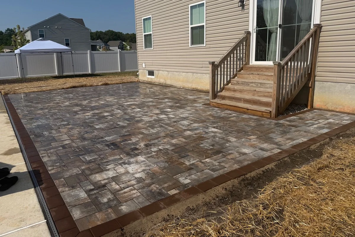 Complete 780 sq ft Cambridge paver patio connected to wooden porch steps with integrated channel drainage in Williamstown, NJ.