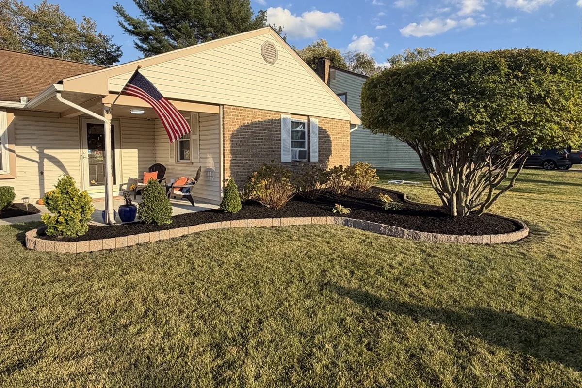 A comprehensive wide-angle view of a complete front and side yard home landscape installation by JPL Landscaping in Washington Township, NJ, featuring continuous, fluidly curved stone edging and clean mulch beds.