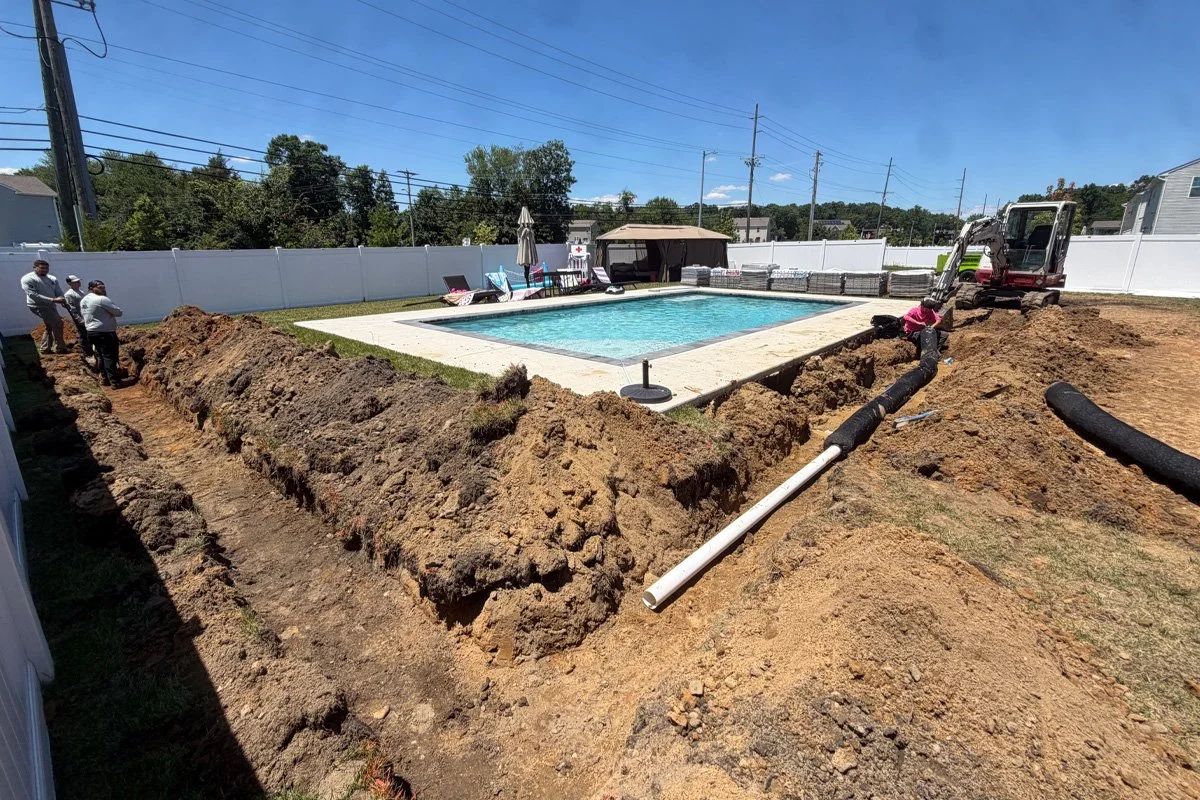 Deep trench excavation and French drain pipe installation along a poolside lawn by JPL Landscaping in Williamstown, NJ.