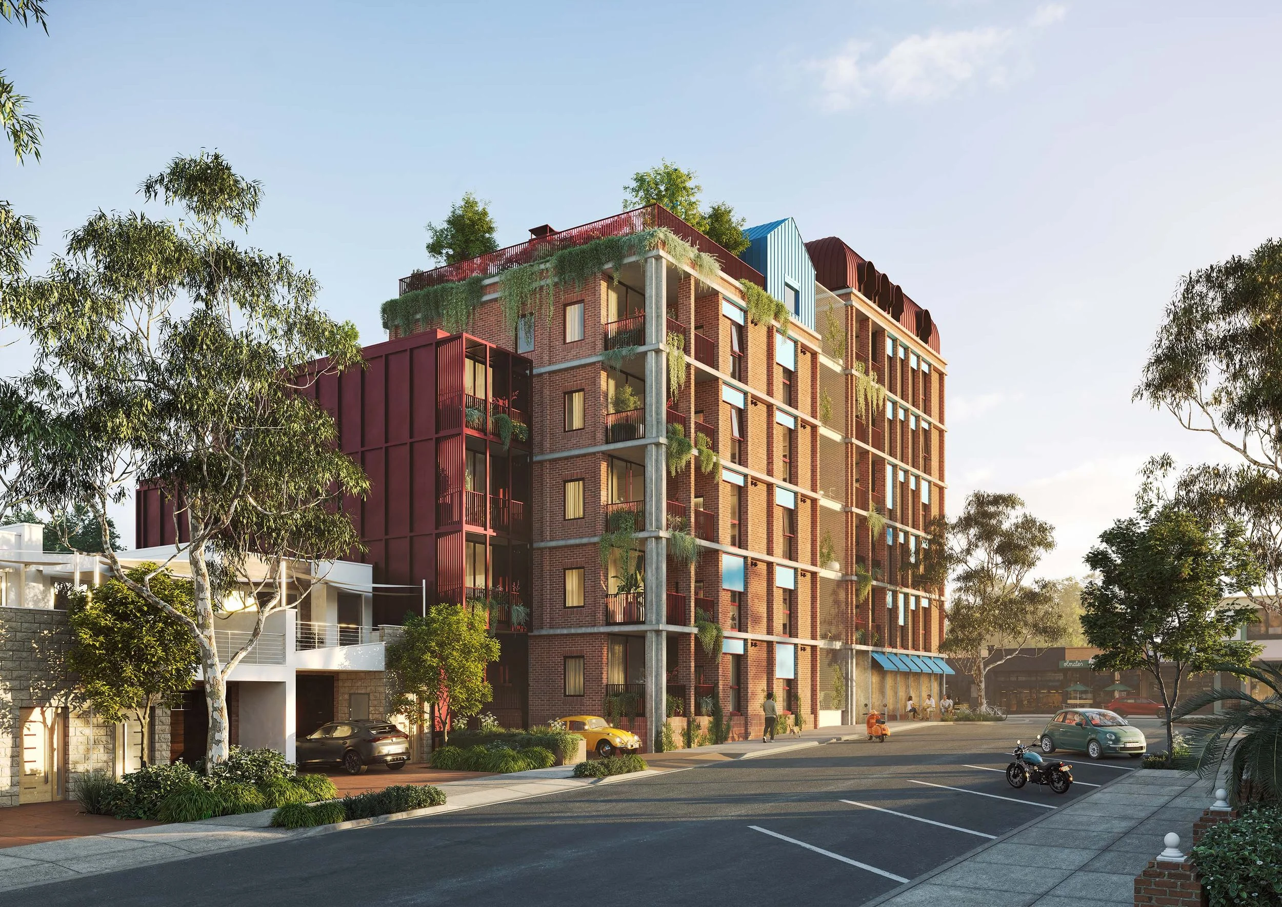 A multi-story brick apartment building with colorful rooftop accents and greenery on balconies, situated near a parking lot with parked cars and a motorcycle, under a clear blue sky with trees surrounding the scene.