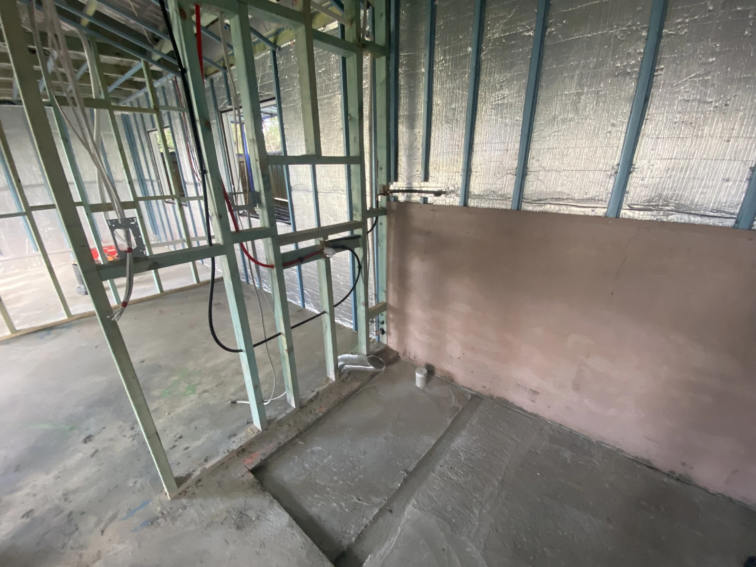 Construction site with steel framing and insulation on walls, unfinished interior space.