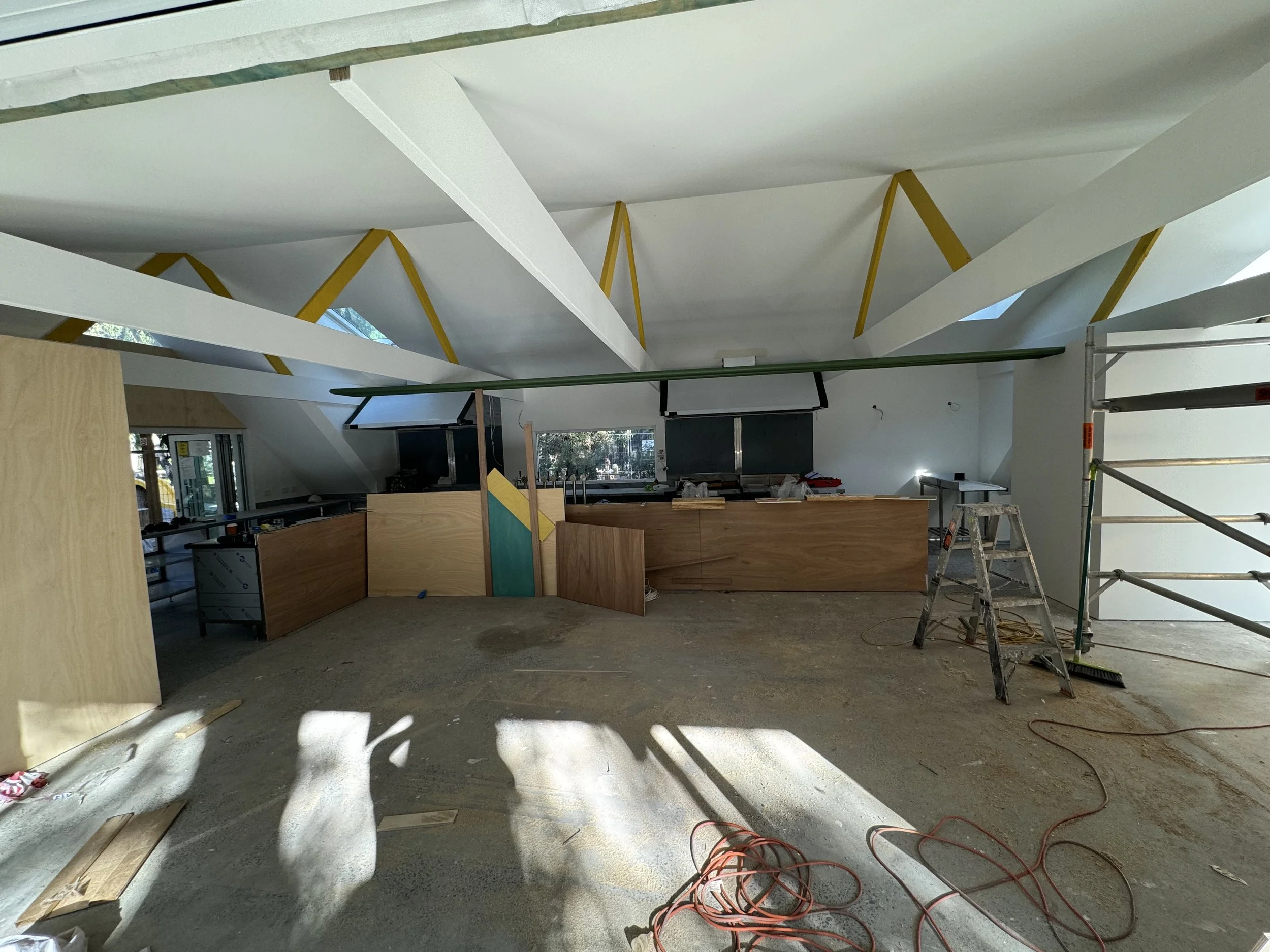 Interior view of a construction site with partially completed walls, scaffolding, and building materials, indicating ongoing building or renovation work.