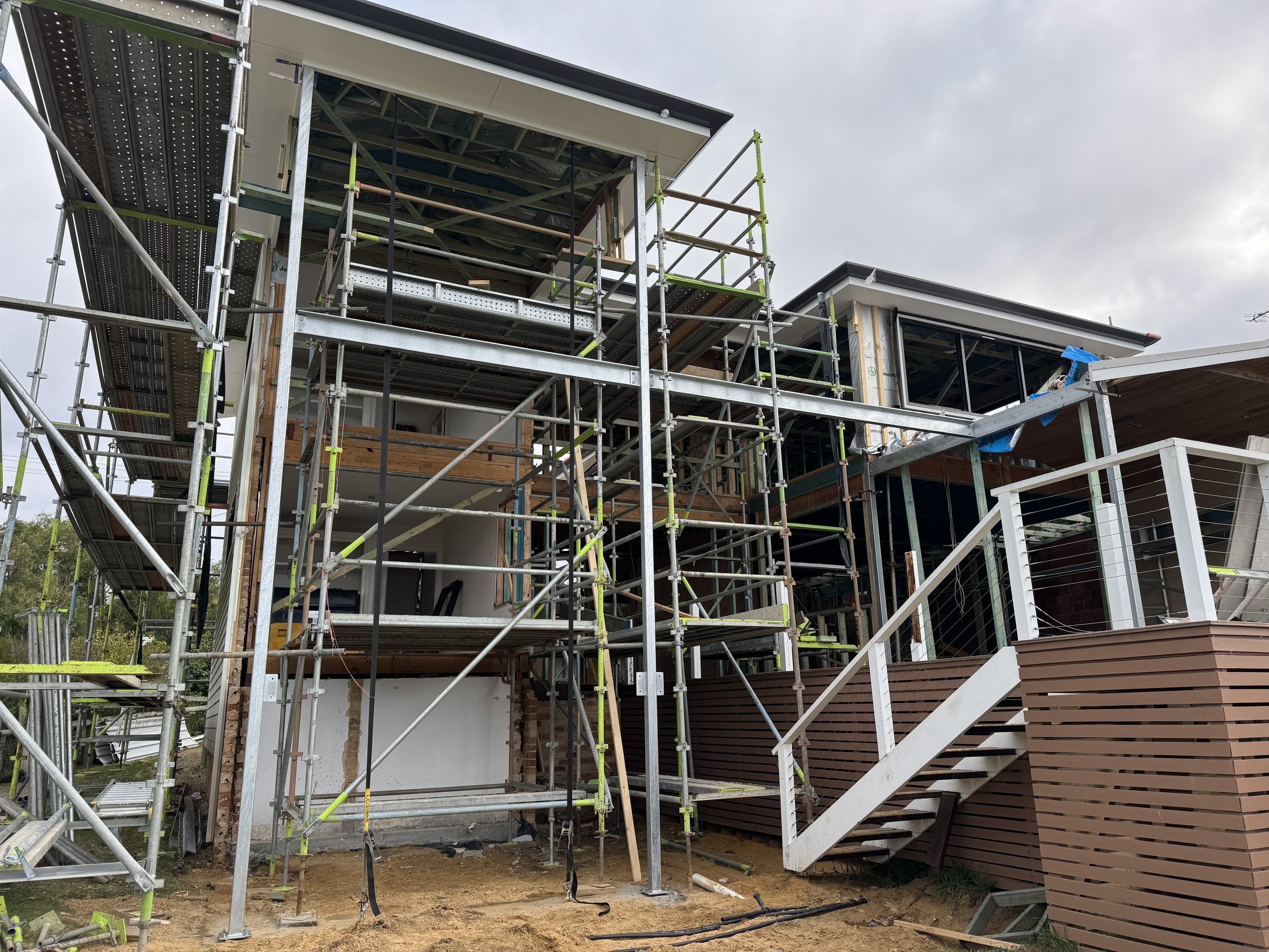 Under construction home with scaffolding, exposed framing, and partially installed exterior siding.