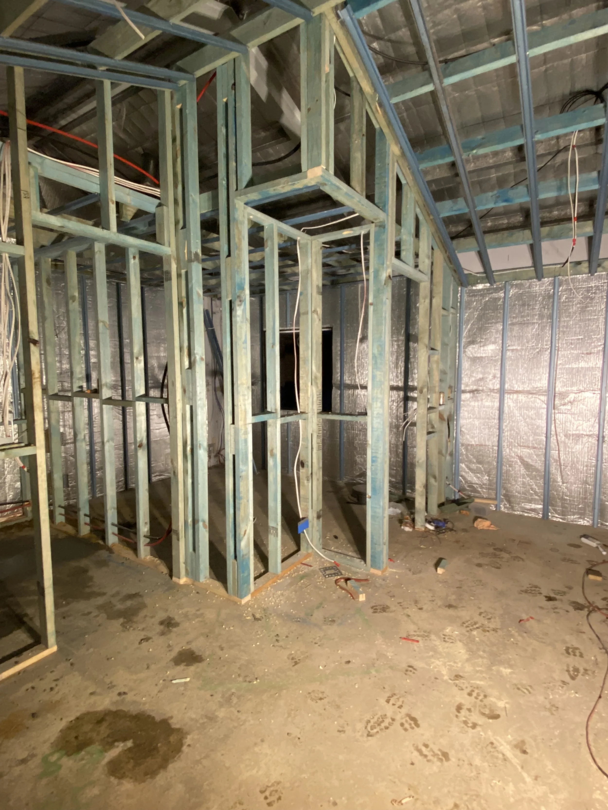 Construction site with metal framing for walls and ceiling, electrical wiring, and unfinished floors.