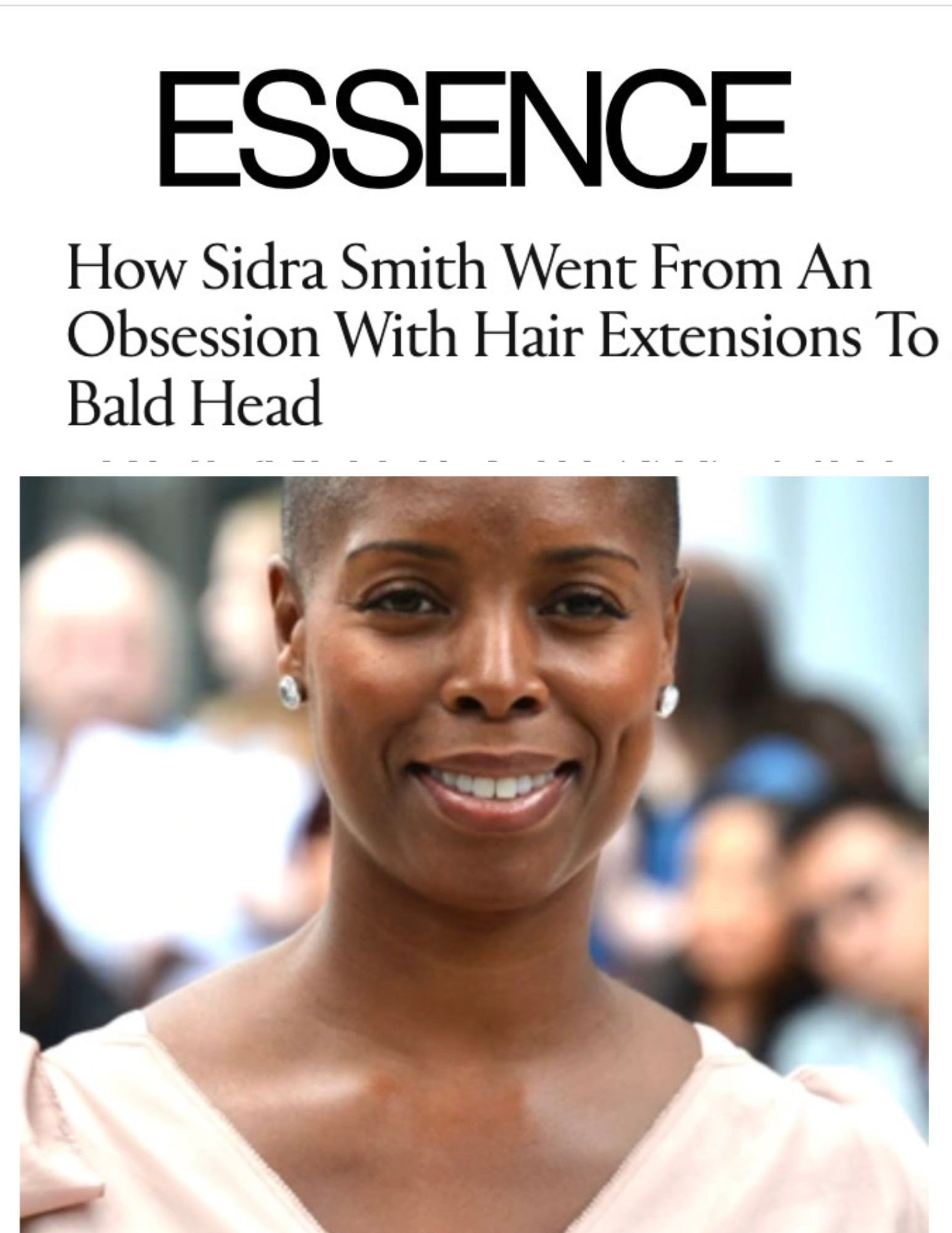 Close-up of a smiling woman, Sidra Smith, with a bald head, wearing earrings, in a crowd of people.