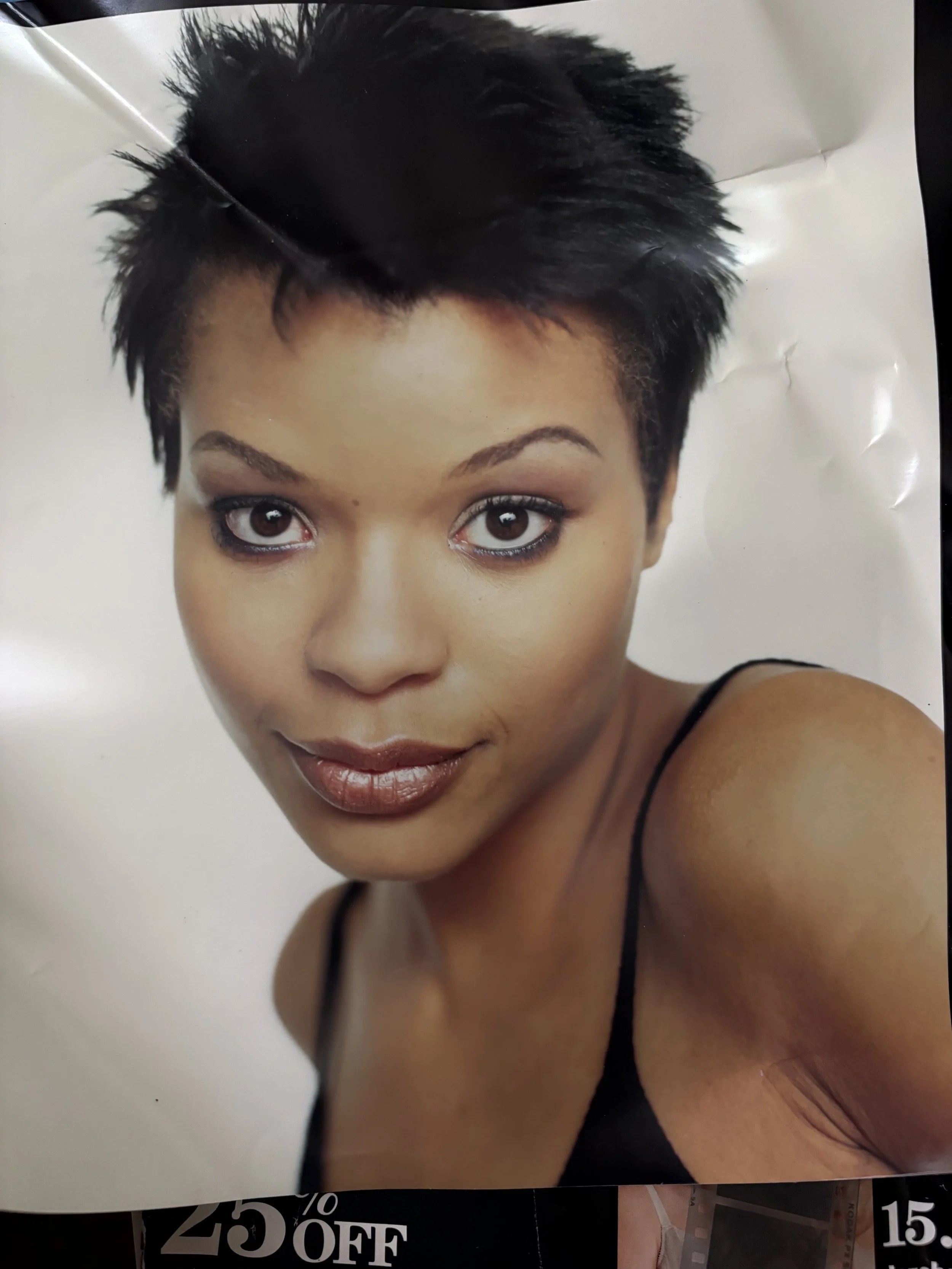 Close-up of Erickka Jones with short, styled black hair, wearing makeup, and a black sleeveless top, looking directly at the camera.