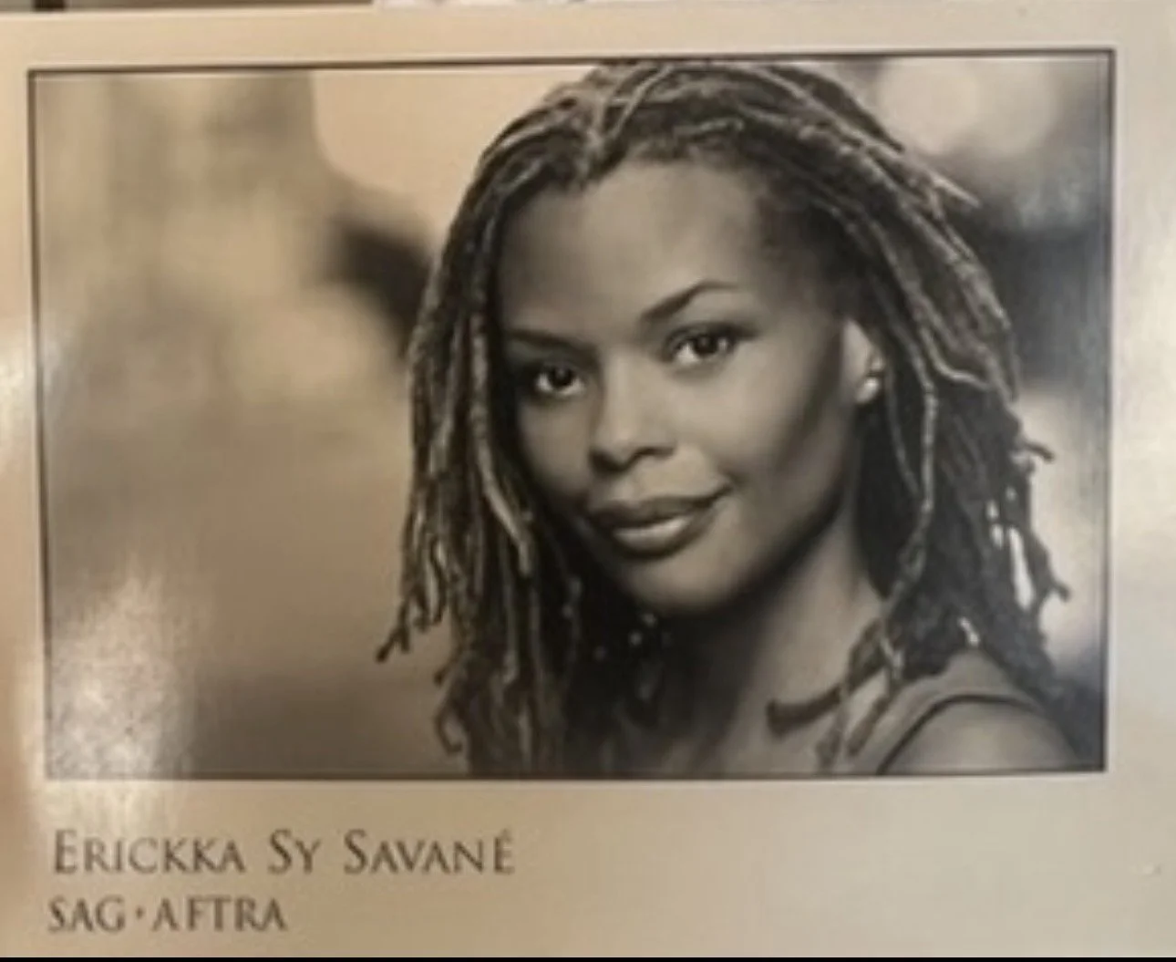 Erickka Jones in a black and white portrait with long locs, smiling softly at the camera for an acting headshot. Photo by Marvin Johns