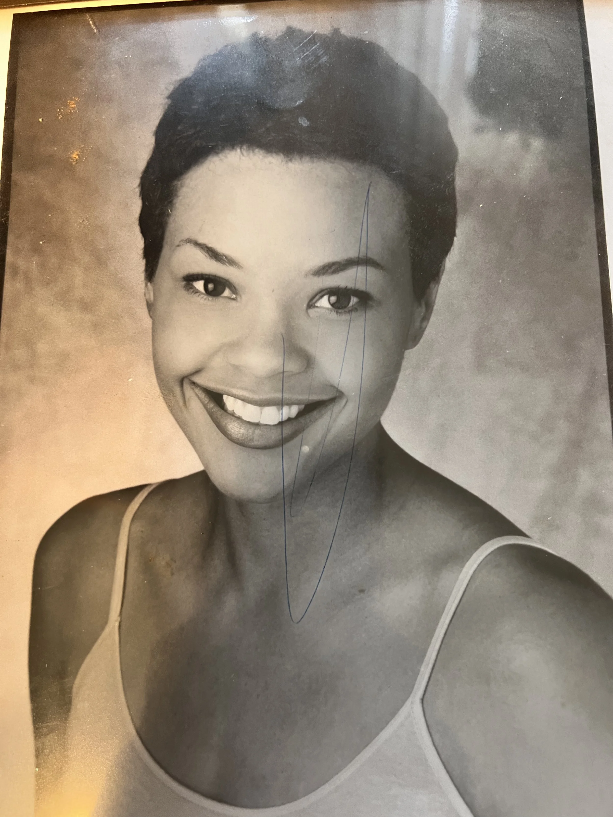 A young Erickka Jones with short, tapered hair, smiling for one of her first acting headshots.  