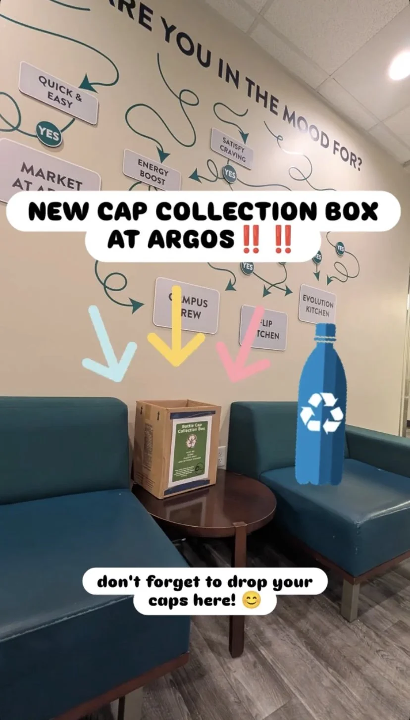 Photo of a waiting area with two teal chairs, a small wooden table, and a cardboard bottle cap collection box. The wall behind has a colorful flowchart, and there are three colorful arrows pointing downwards towards the collection box, which is labeled 'Bottle Cap Collection Box.' Overlay text promotes a new cap collection box at Argos and reminds people to drop their caps.
